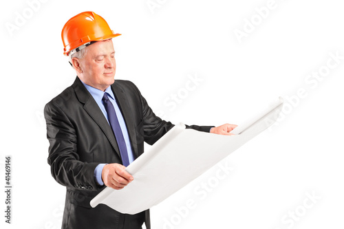 Photo: A mature construction worker with helmet holding blueprint A mature construction worker with helmet holding blueprint