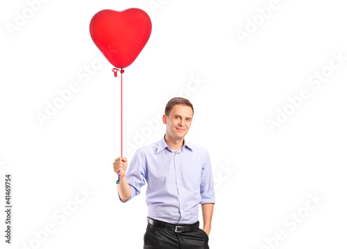 Foto: A smiling young male holding a red heart shaped balloon A smiling young male holding a red heart shaped balloon