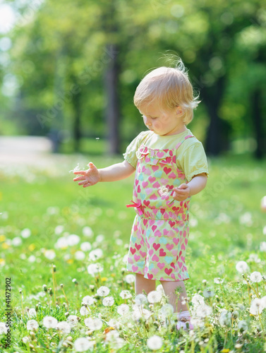 Photo: Baby playing with dandelions in park Baby playing with dandelions in park