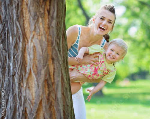 Photo: Smiling mother and baby looking out from tree Smiling mother and baby looking out from tree