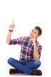 seated young casual man pointing at something up seated young casual man pointing at something up