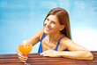 Ältere Frau mit Cocktail im Pool