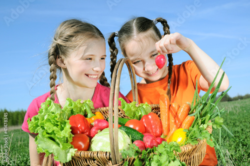 Photo: Two little girls with basket of vegetables Two little girls with basket of vegetables