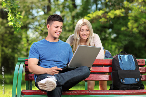 Photo: Young male and female working on a laptop in a park Young male and female working on a laptop in a park