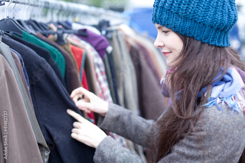 Foto: Woman choosing clothes at the flea market. Woman choosing clothes at the flea market.