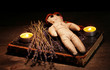 Voodoo doll girl on a wooden table in the candlelight