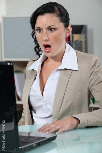 Photo: businesswoman looking at her laptop open mouthed businesswoman looking at her laptop open mouthed