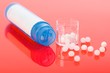Homeopathic pills and container on red