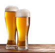 Two glasses of beers on a wooden table.