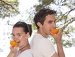 Foto: Young cute couple eating fresh orange in their garde Young cute couple eating fresh orange in their garde