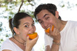 Foto: Young cute couple eating fresh orange in their garden Young cute couple eating fresh orange in their garden