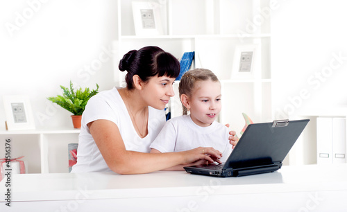 Photo: Mom and daughter are working together for a laptop Mom and daughter are working together for a laptop