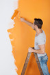 mann streicht eine wand mit farbrolle