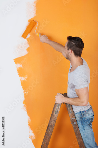Photo: mann streicht eine wand mit farbrolle mann streicht eine wand mit farbrolle