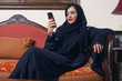 arabian lady wearing hijab chatting using mobile phone