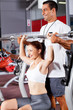 young fitness woman with personal trainer in gym