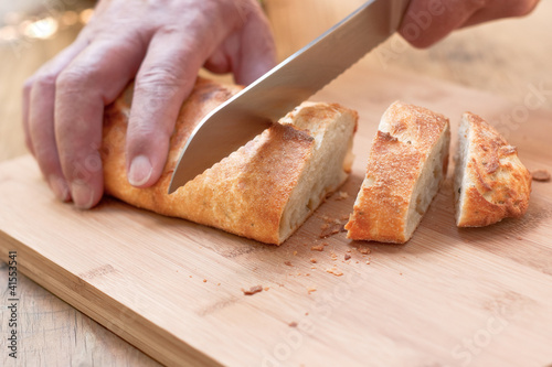 Photo: Male hands slicing rustic, home-baked peppercorn bread. Male hands slicing rustic, home-baked peppercorn bread.