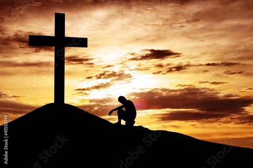 Photo: Man sitting desperately under the cross Man sitting desperately under the cross