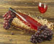 Bottle of pink wine in a basket and fresh grapes on a table
