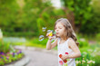 Cute curly girl  blowing  soap bubbles