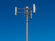 Mobile phone antennas on metal tower on blue sky Mobile phone antennas on metal tower on blue sky