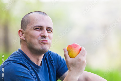 Photo: Man eating an apple outdoor Man eating an apple outdoor