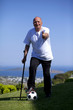 A senior football player with walking stick holding a soccerball