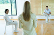 Woman leading group therapy session, rear view