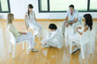 Man sitting on floor in middle of group sitting in chairs, talking