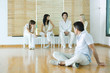 Man sitting on floor, looking over shoulder at group sitting in chairs