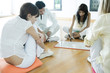 Adults sitting on cushions on floor, one woman drawing on drywipe board