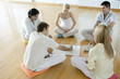 Group of adults sitting on cushions on floor, one man drawing on drywipe board