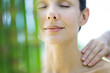 Woman having massage, smiling, bamboo in blurred foreground