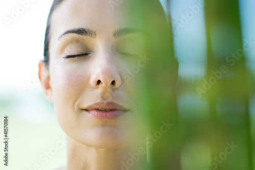 Photo: Woman closing eyes, smiling, bamboo in blurred foreground Woman closing eyes, smiling, bamboo in blurred foreground