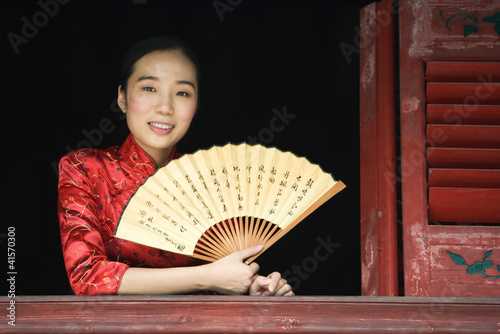 Foto: Young woman wearing traditional Chinese clothing, holding fan Young woman wearing traditional Chinese clothing, holding fan