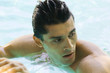 Man in swimming pool, looking over shoulder, close-up