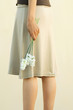 Woman in skirt holding flowers, cropped view