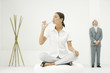 Photo: Professional woman sitting on ottoman, drinking from water bottle, businessman and bamboo in background Professional woman sitting on ottoman, drinking from water bottle, businessman and bamboo in background