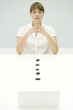Woman sitting with eyes closed and hands clasped, line of stones leading to laptop