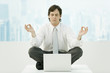 Businessman meditating in office, eyes closed