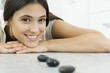 Photo: Young woman lying on stomach, resting head on arms, behind small black stones in a line Young woman lying on stomach, resting head on arms, behind small black stones in a line