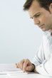 Man using calculator, sitting at table, side view
