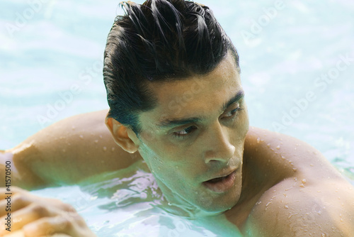 Photo: Man in swimming pool, looking over shoulder, close-up Man in swimming pool, looking over shoulder, close-up