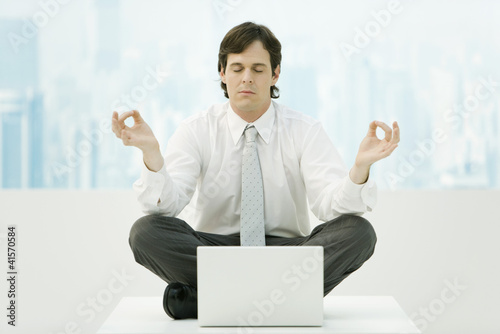 Photo: Businessman meditating in office, eyes closed Businessman meditating in office, eyes closed