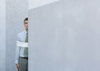 Businessman tied up, standing partially hidden behind wall
