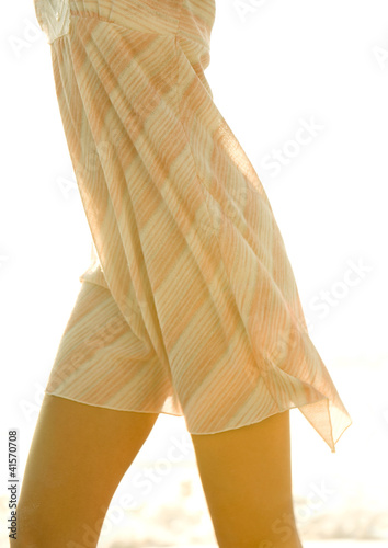 Photo: Woman's mid-section, wearing light dress Woman's mid-section, wearing light dress
