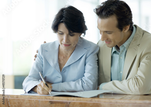 Photo: Couple signing document at counter Couple signing document at counter