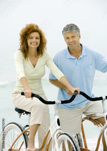 Photo: Couple riding bikes on beach Couple riding bikes on beach