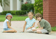 Three children playing marbles outdoors