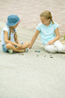 Two girls playing marbles in street